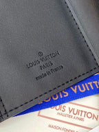 Small dark leather wallet close-up with stamped brand text and stitched edge