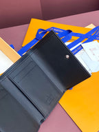 Small dark leather wallet with card slots, visible stitching and snap button
