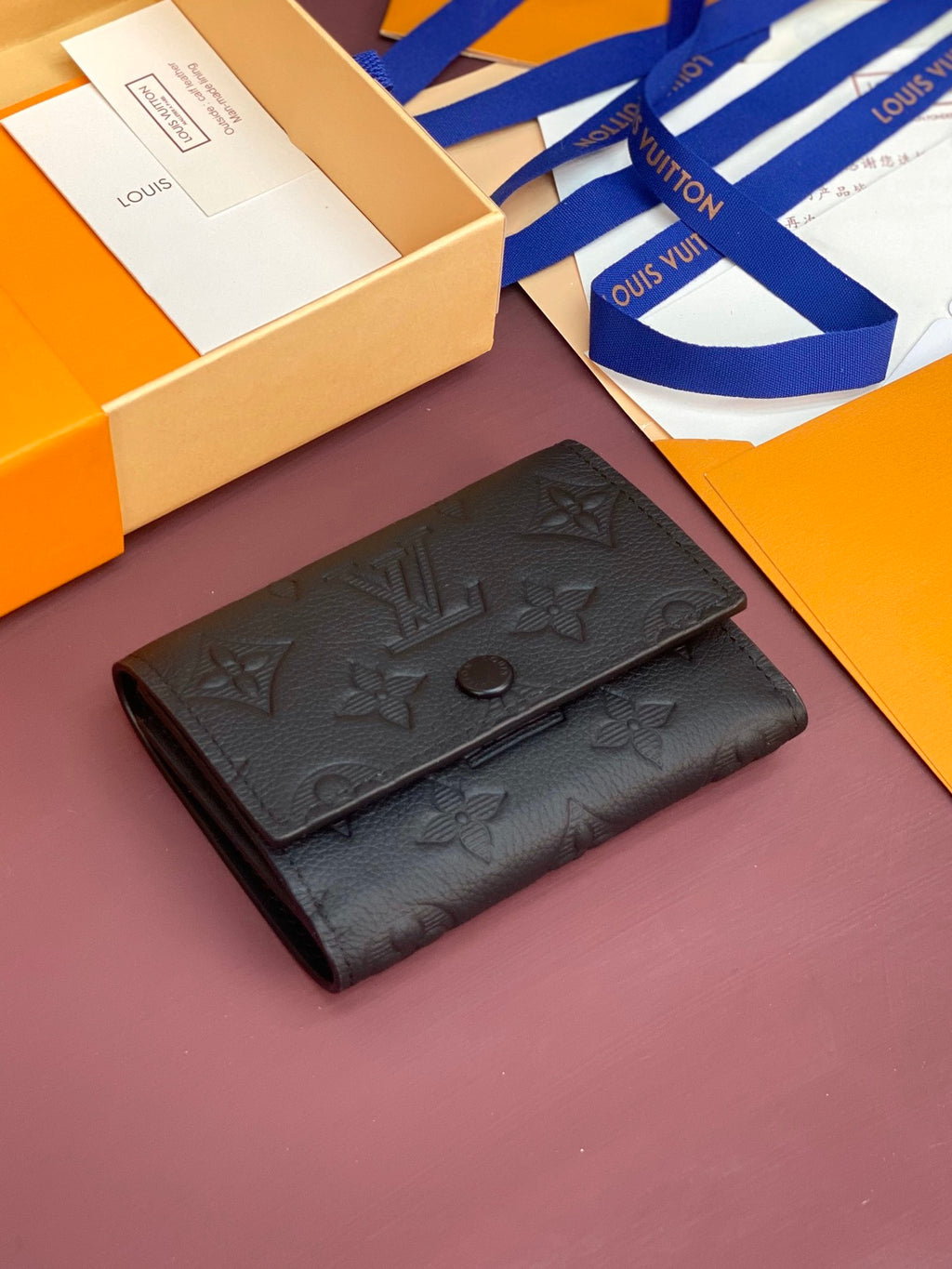 Small black leather wallet with embossed monogram and snap closure, angled view