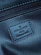 Close-up of embossed monogram leather label on toiletry bag with stitched edge