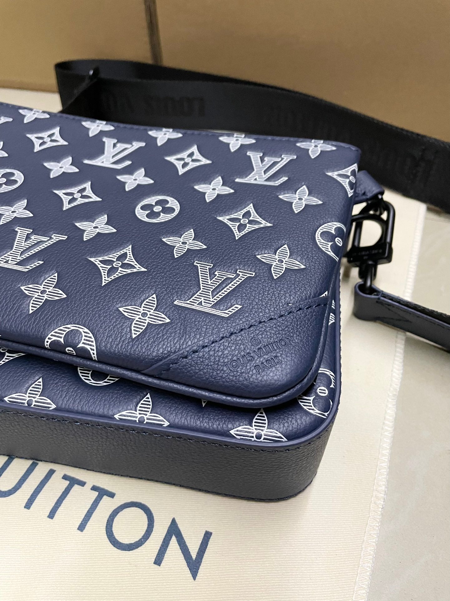 Men's Louis Vuitton bag corner, navy monogram canvas with stitched leather trim.