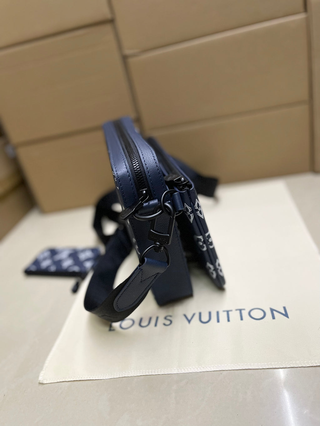 Louis Vuitton crossbody bag, side view with leather strap and navy monogram canvas