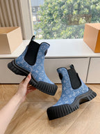 Blue monogram Chelsea boots held in hand, black elastic panels and thick ribbed soles
