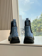 Back view of blue monogram Chelsea boots with black heel panels and treaded rubber soles