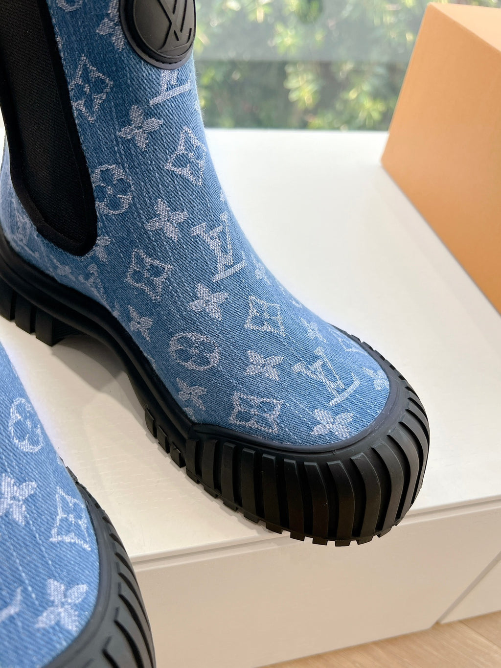 Close-up of blue monogram Chelsea boot toe with black ribbed sole and elastic side