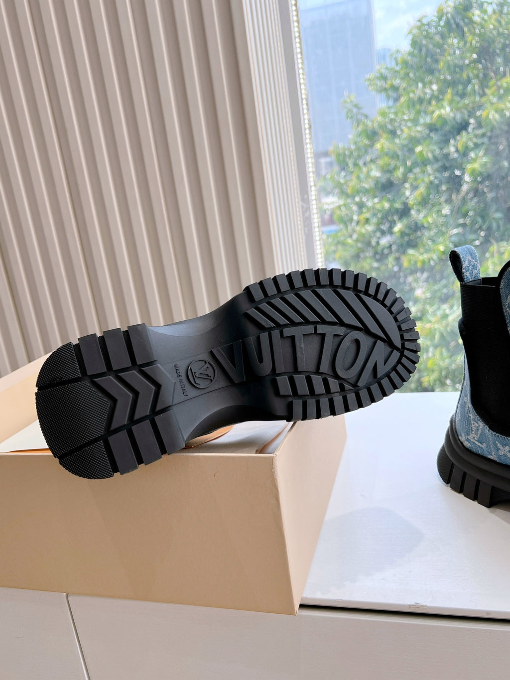 Outsoles of blue monogram Chelsea boots with black rubber tread and chunky ridged sole