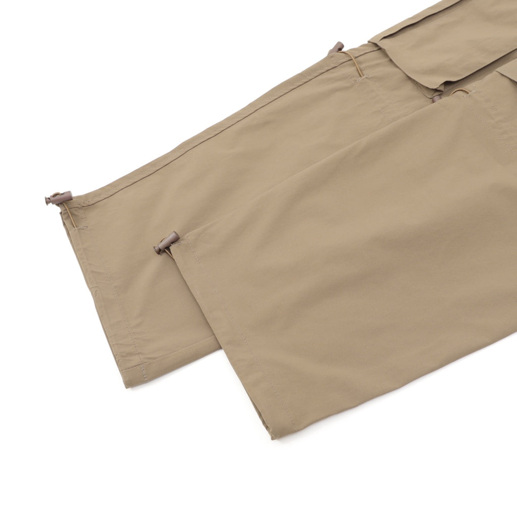 Beige shorts hem close-up with side button tabs and drawstring ends