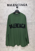 Green long-sleeve T-shirt on hanger with large black Balenciaga logo print
