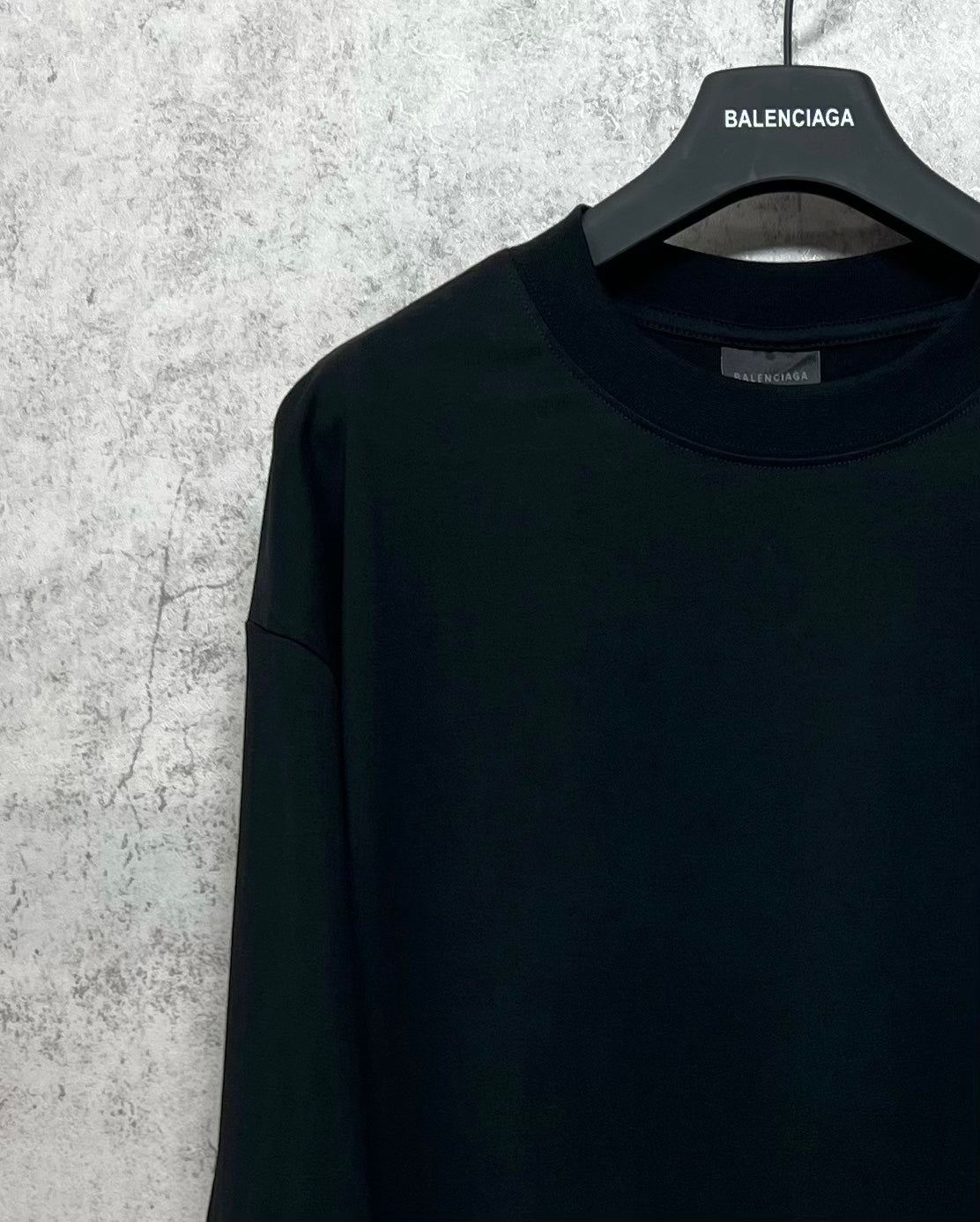 Dark long-sleeve T-shirt close-up at neckline with brand label