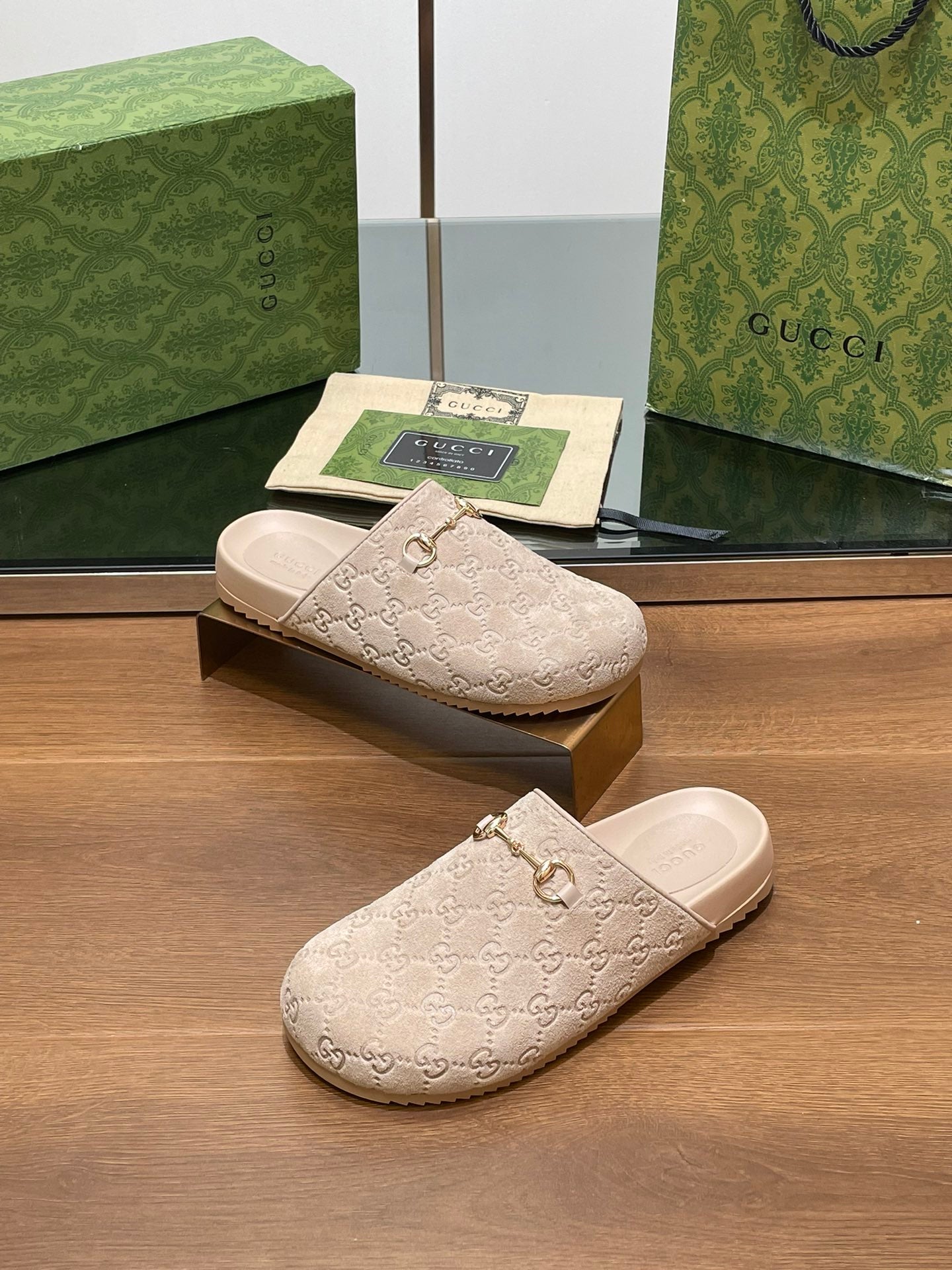 Gucci logo slide sandals, light beige upper with interlocking G pattern and gold horsebit
