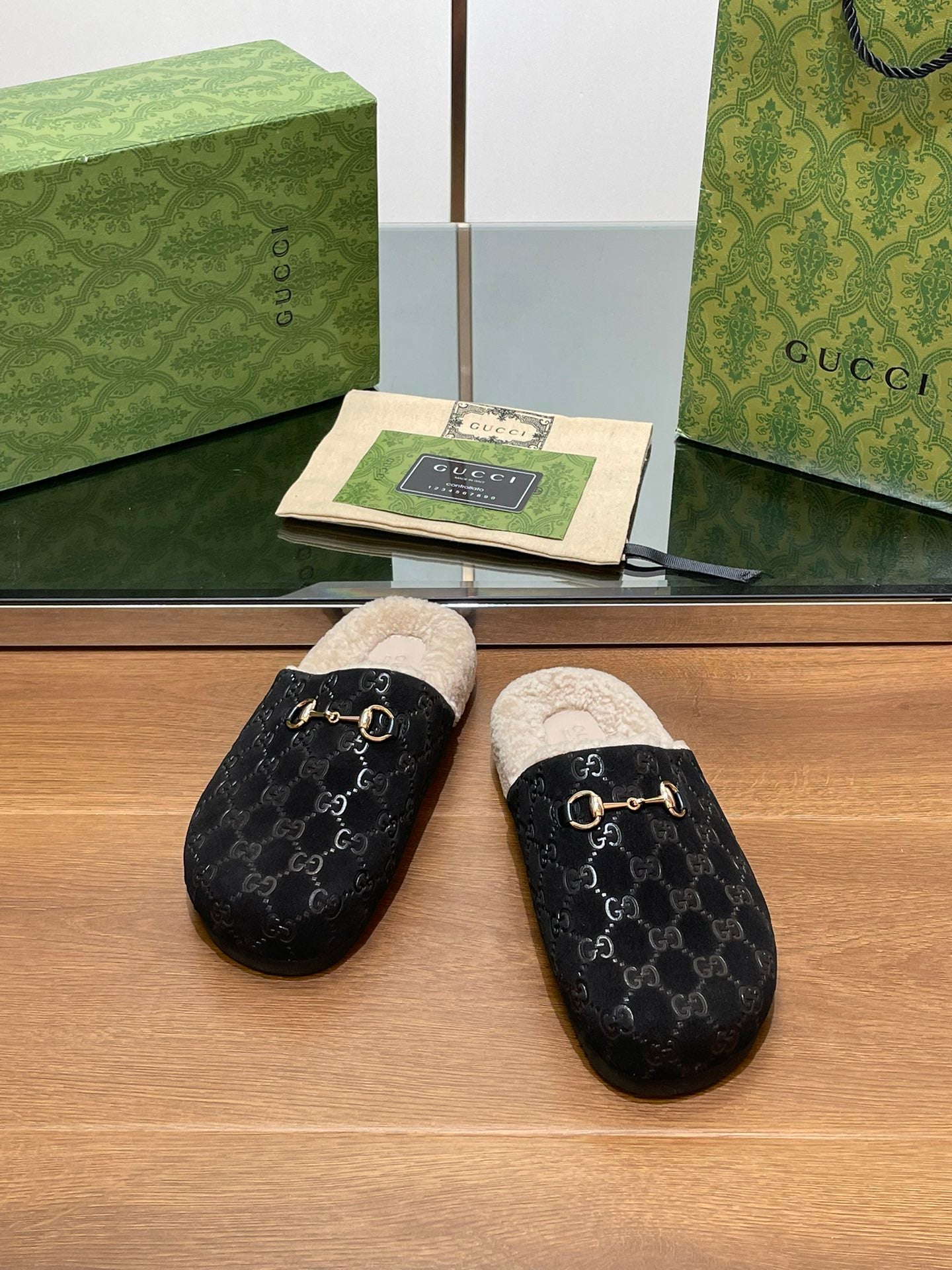 Black monogram mule slippers with beige shearling lining and gold-tone ring detail