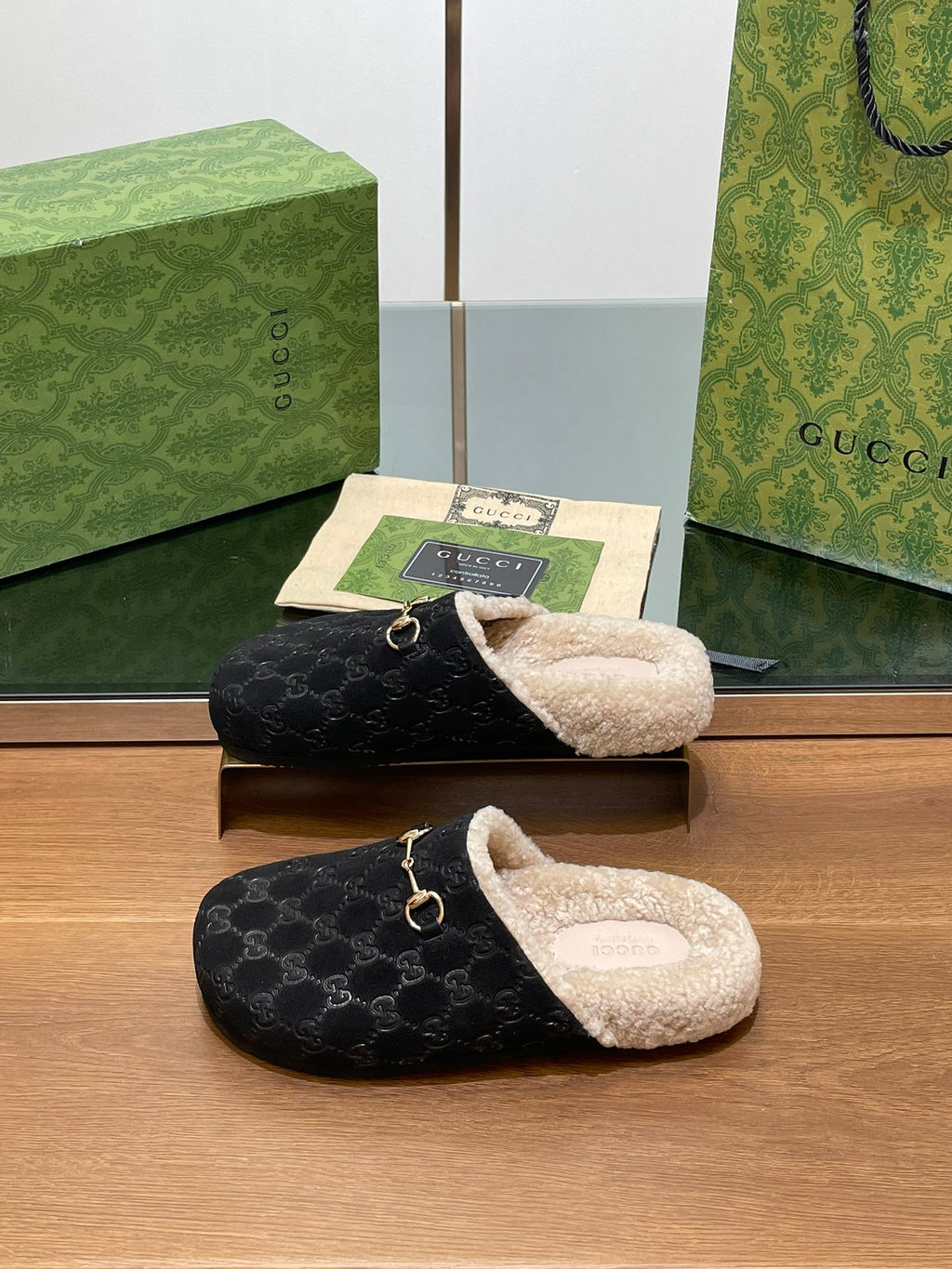 Pair of black monogram mule slippers with beige shearling lining and gold-tone horsebit