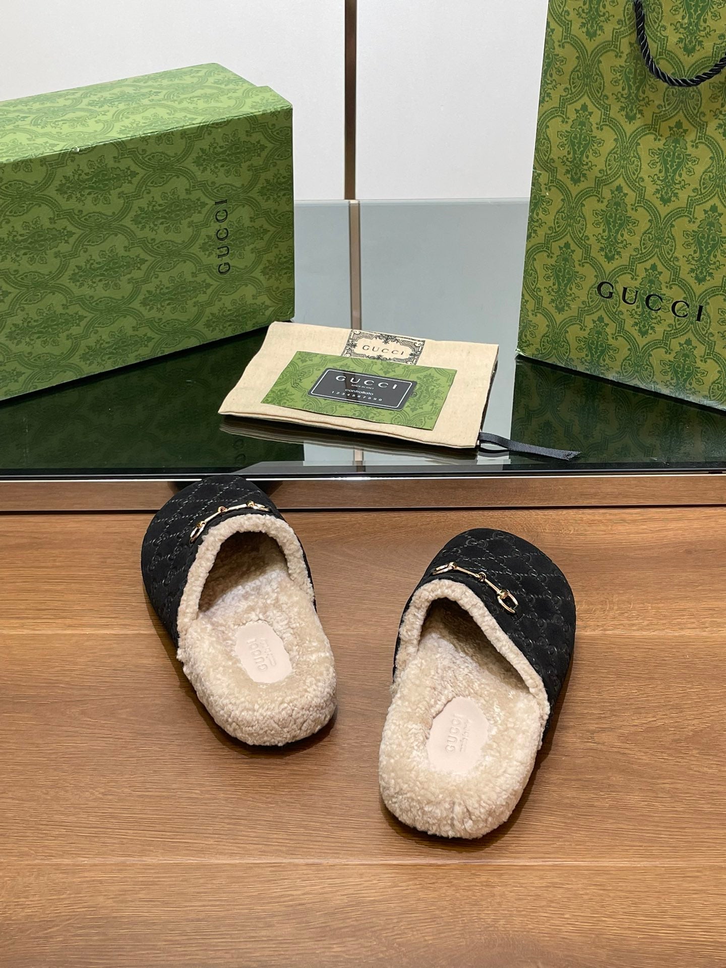Black monogram mule slippers with open back and beige shearling lining, gold-tone accent