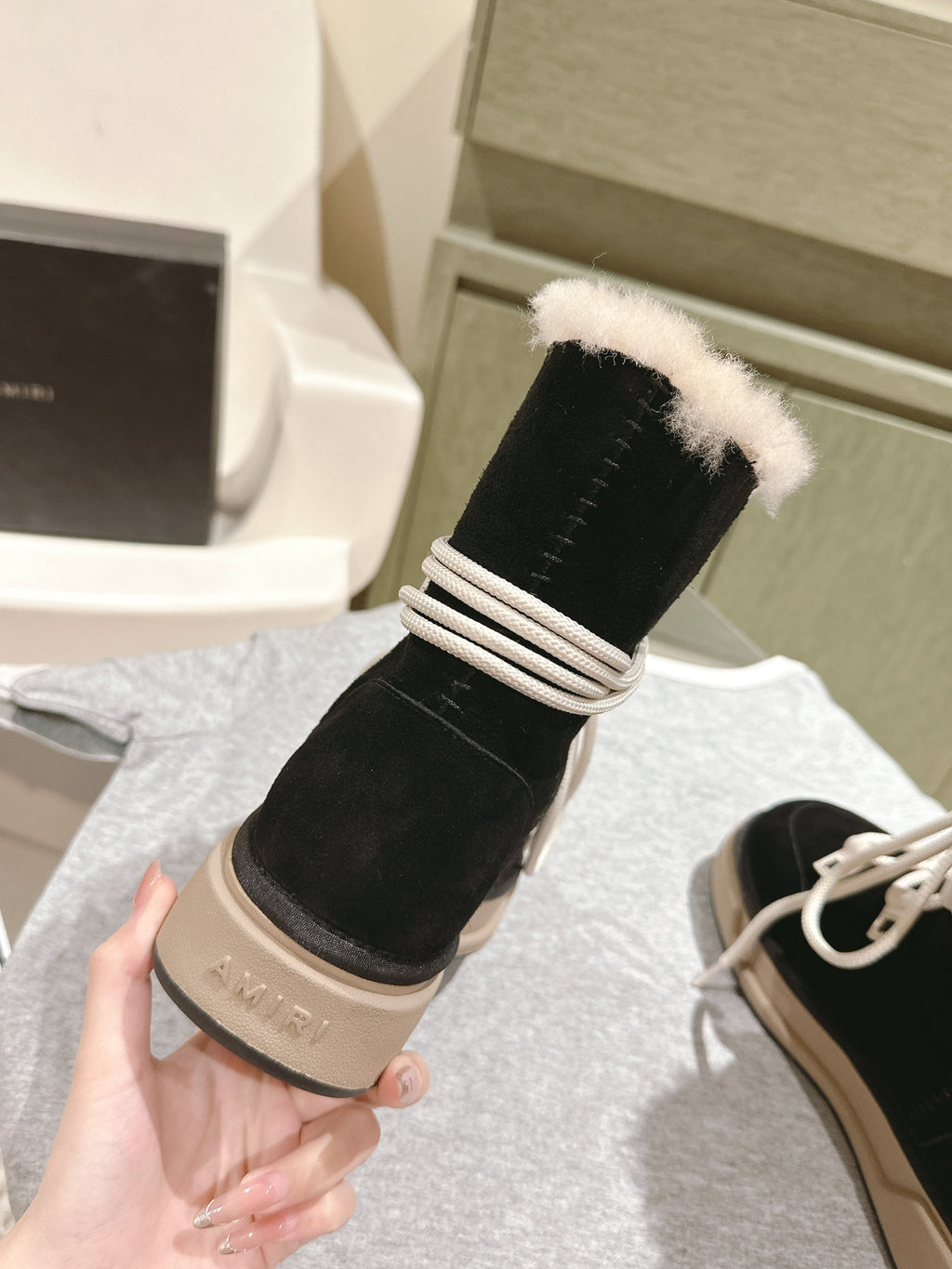 Black lace-up high-top boot with faux-fur cuff and beige sole, side view.