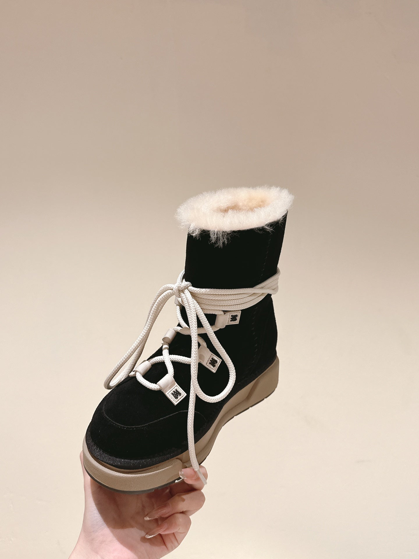 Black lace-up high-top boot with white laces and faux-fur cuff, beige sole.