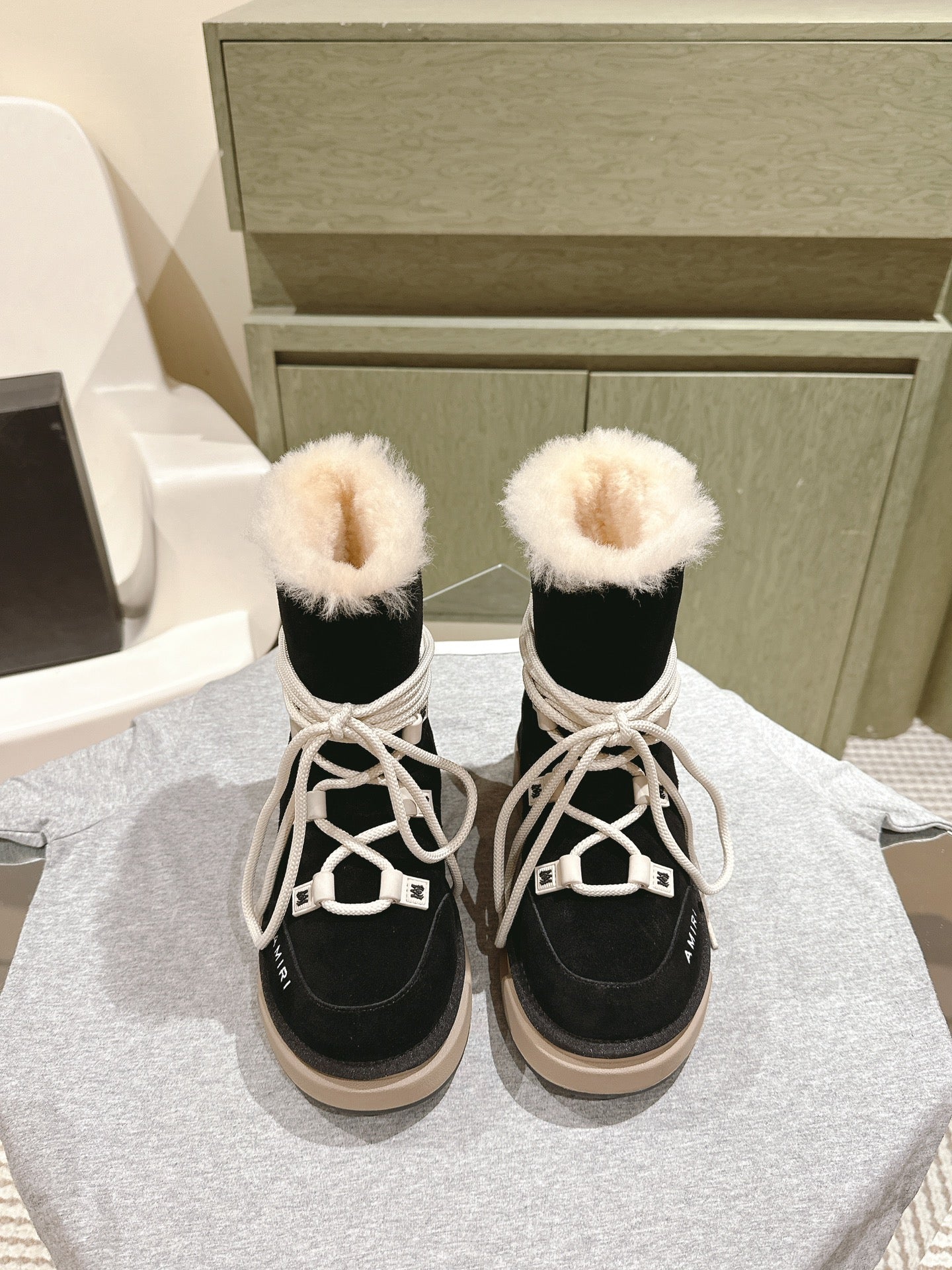 Black high-top boots with white laces and faux-fur cuffs, beige rubber soles.