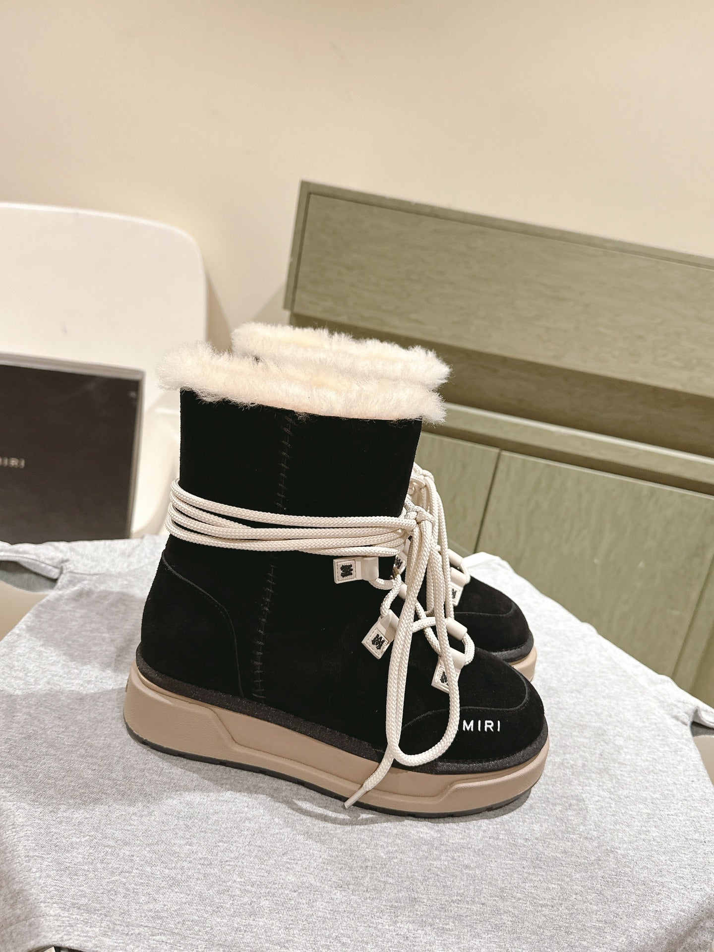 Black high-top boots with white laces, faux-fur cuff and beige lug sole.