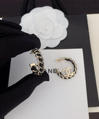 Gold-tone chain hoop earrings with CC logo, held by gloved hand