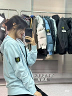 Light blue Stone Island zip-up hoodie with drawstring hood, front zip, and sleeve logo patch