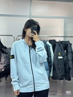 Light blue Stone Island zip-up hoodie with drawstring hood and logo patch on sleeve