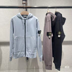 Stone Island zip-up hoodies on hangers: light blue, mauve, and dark navy with logo patches