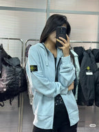 Light blue Stone Island zip-up hoodie, side view with sleeve logo patch and black zipper