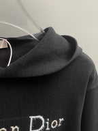 Black hoodie shoulder and hood with embroidered 'Dior' detail.