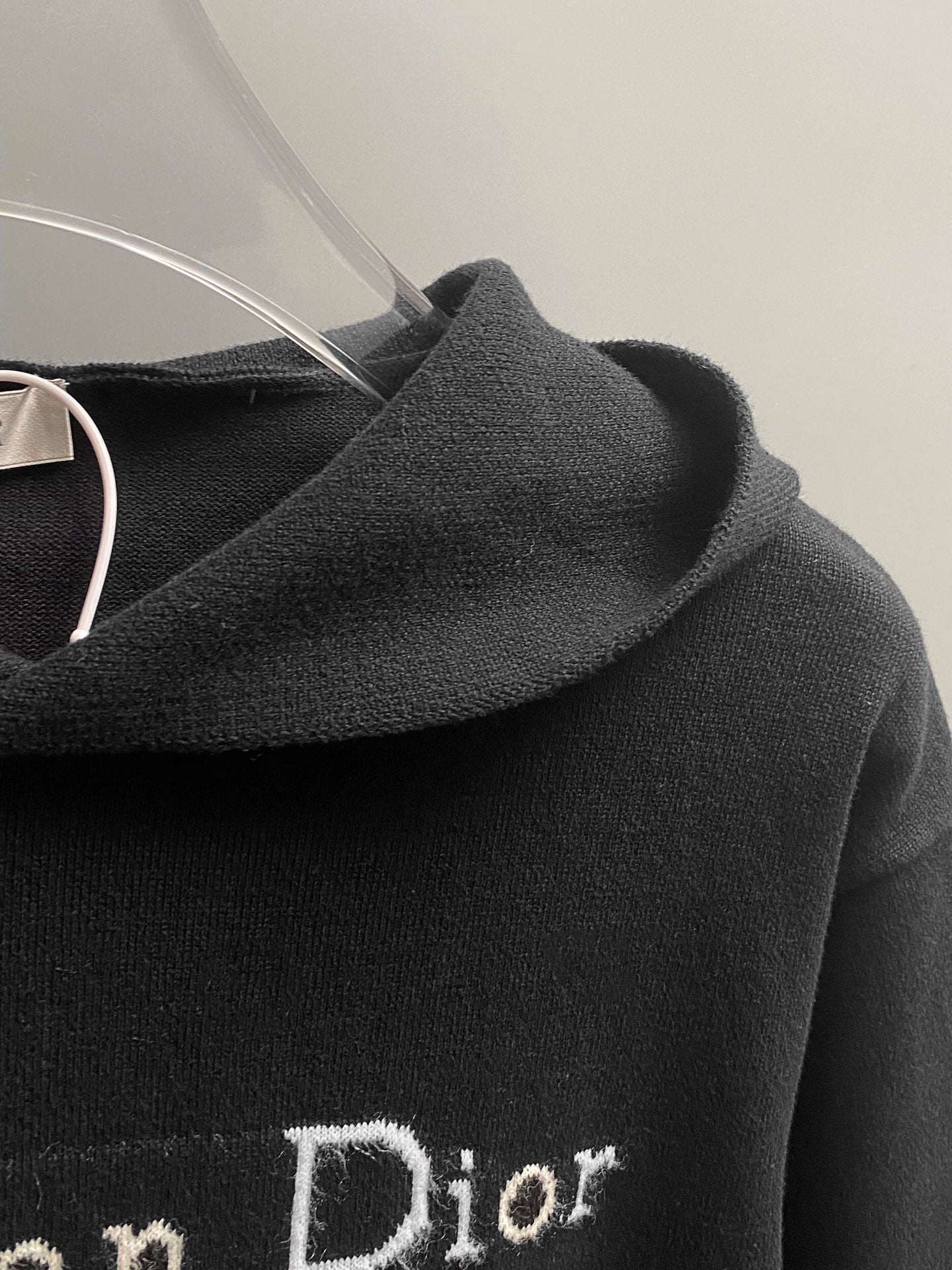 Black hoodie shoulder and hood with embroidered 'Dior' detail.