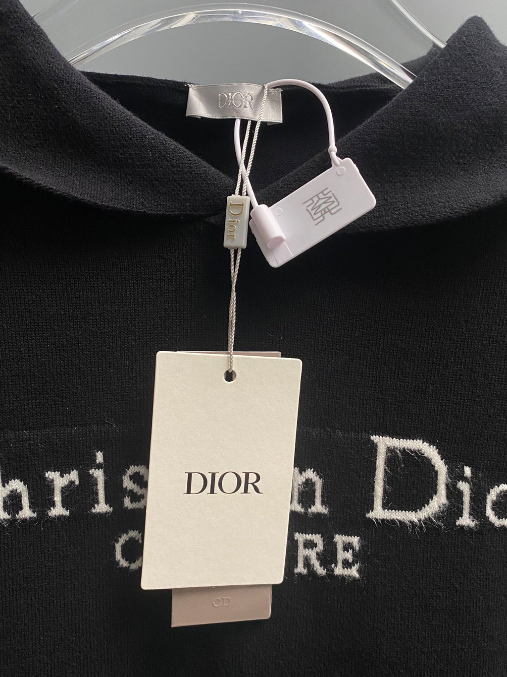 Black hoodie neckline with Dior label and hanging white price tags.