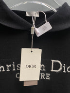 Black hoodie neckline with Dior label and hanging white price tags.