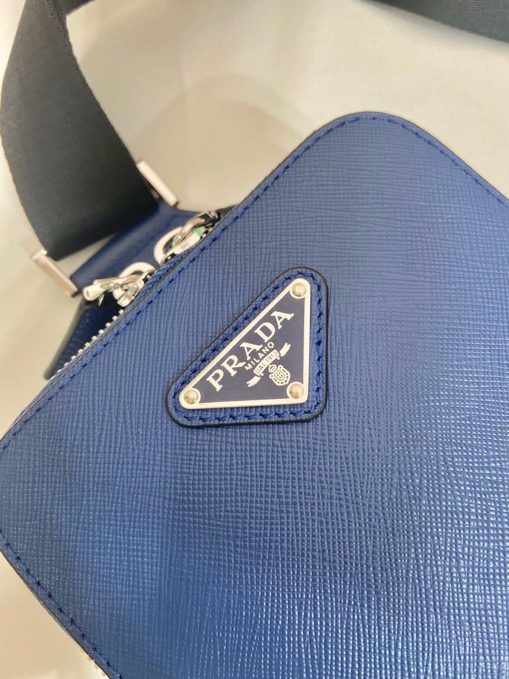 Blue textured leather bag with Prada logo patch on the front panel