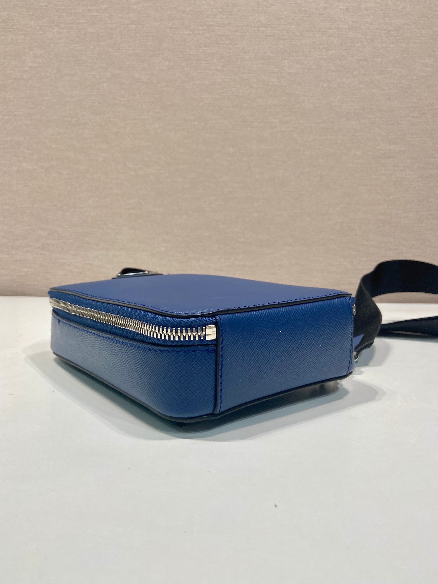 Blue mini crossbody bag side view with gold-tone zipper and black strap