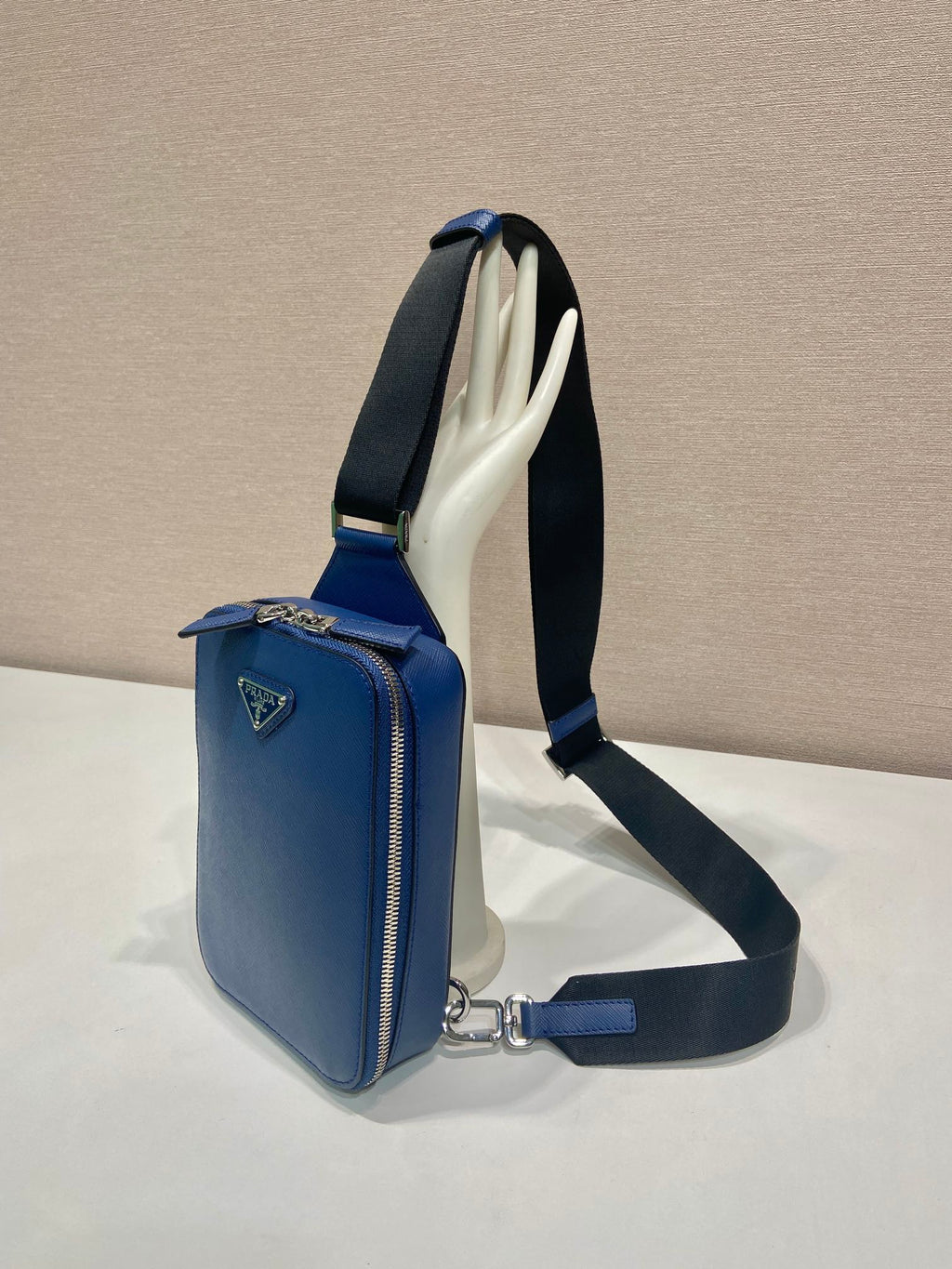 Blue mini crossbody bag with open interior showing light lining and black strap