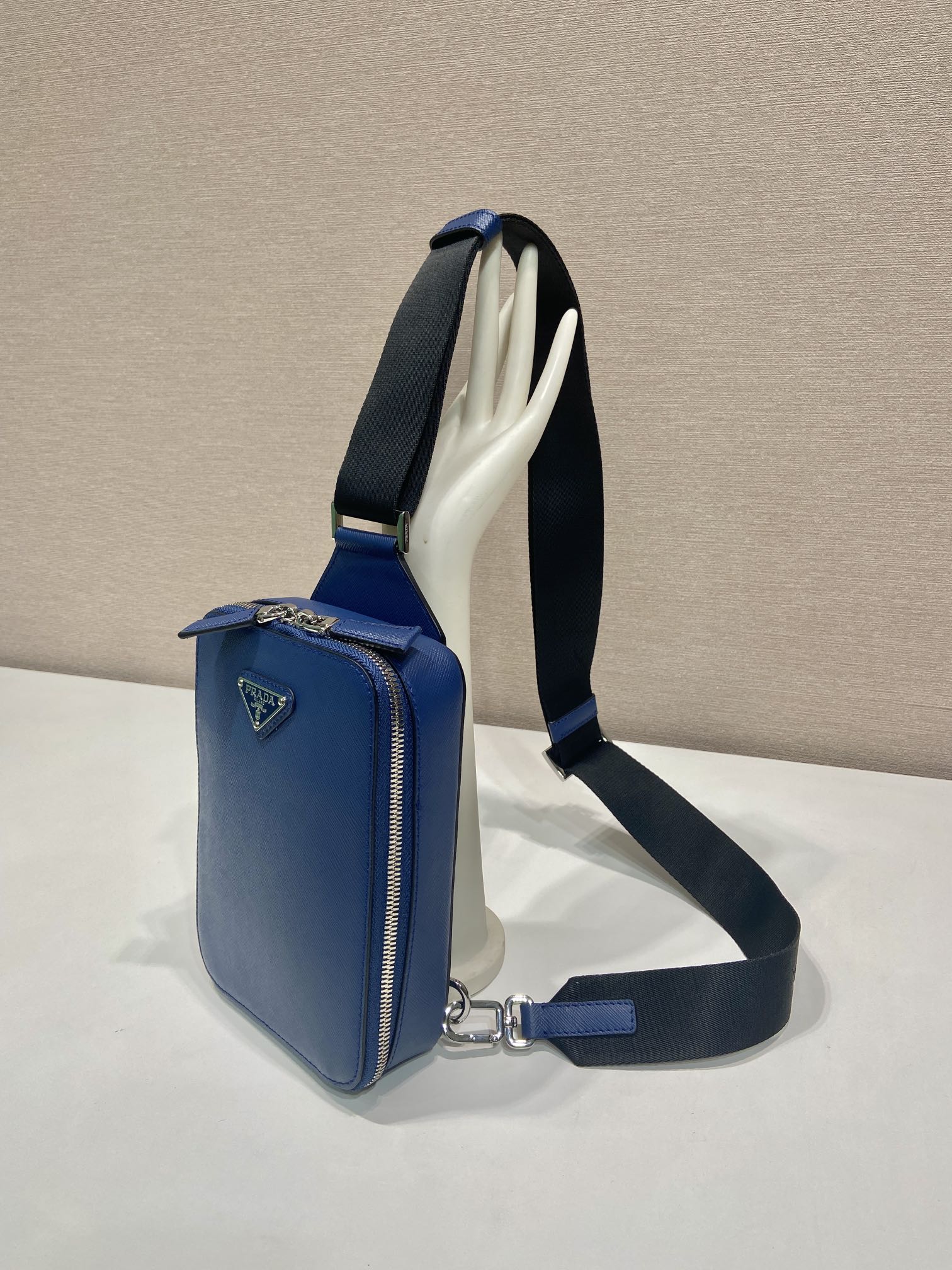 Blue mini crossbody bag with open interior showing light lining and black strap