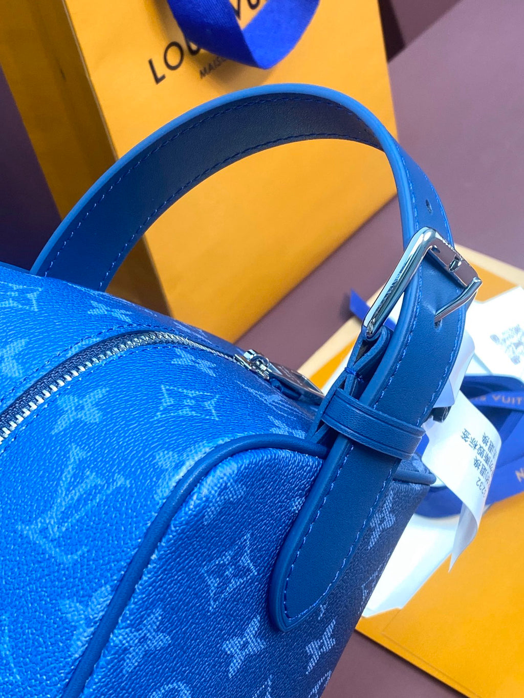Louis Vuitton blue monogram bag with adjustable leather handle strap and buckle