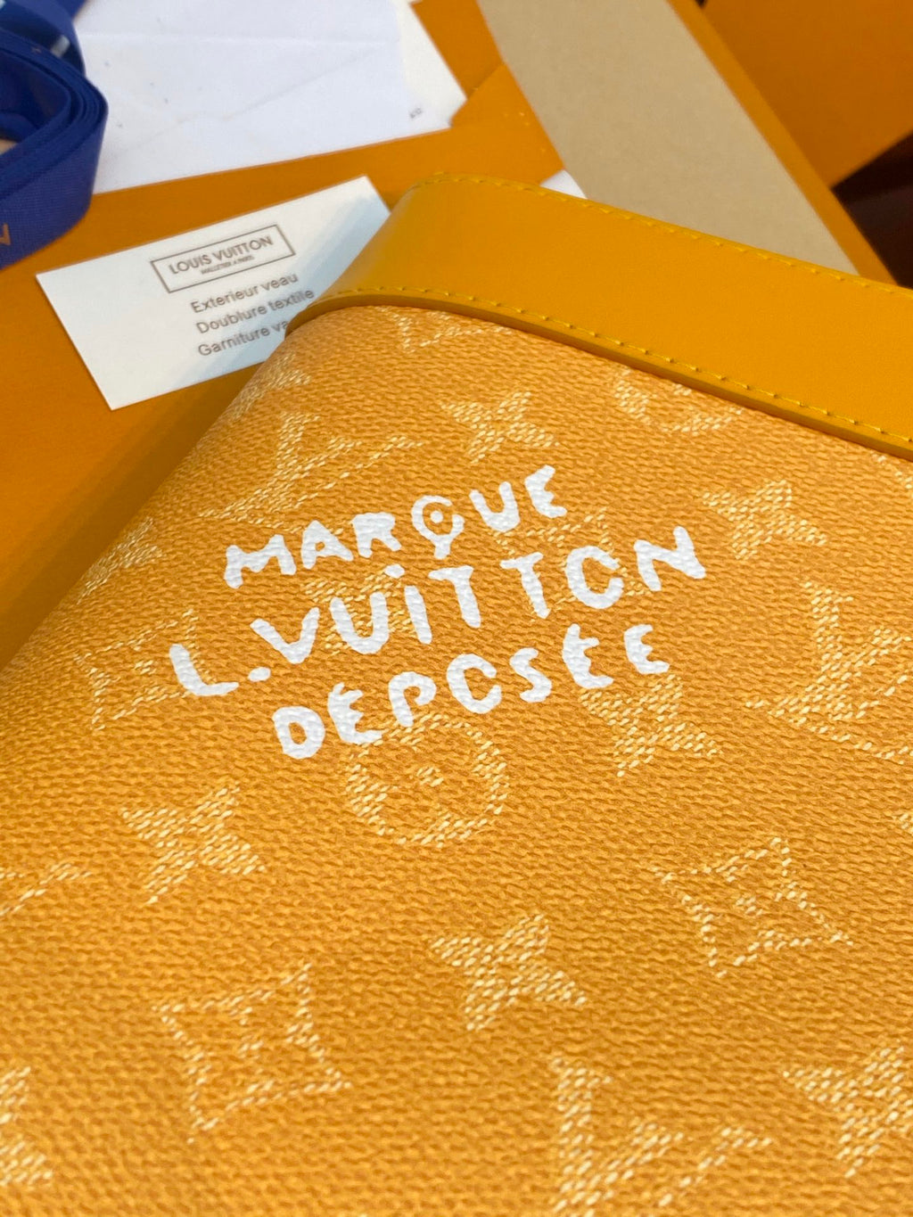 Yellow monogram bag exterior close-up with bold white lettering