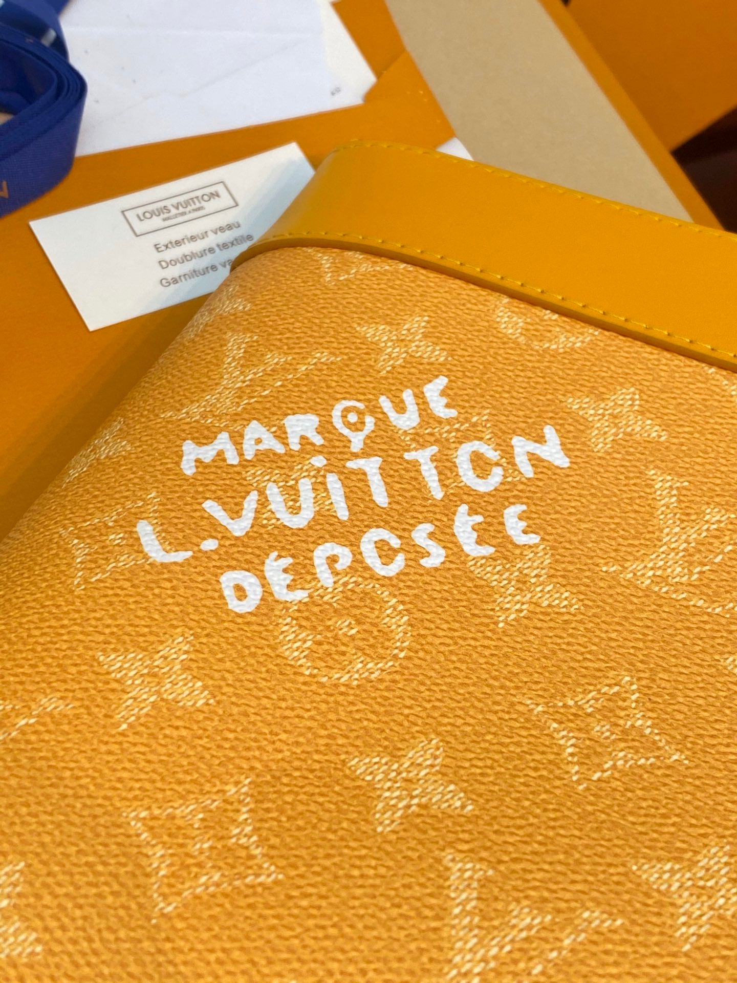Yellow monogram bag exterior close-up with bold white lettering