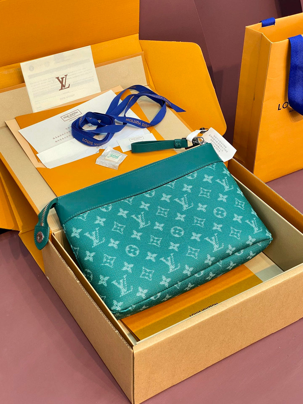 Teal Louis Vuitton monogram bag with top zipper, blue shoulder strap, and logo pattern