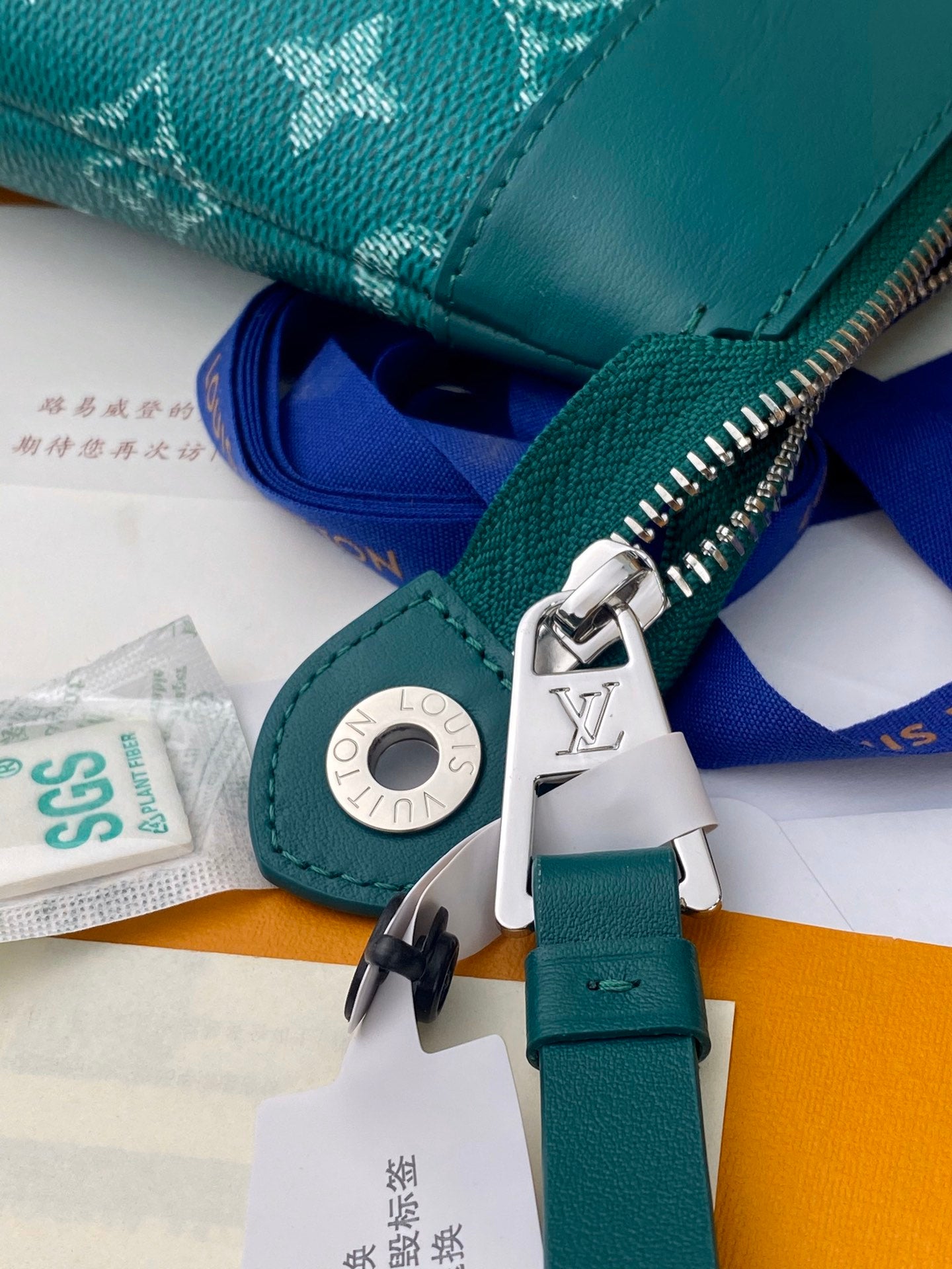 Teal Louis Vuitton monogram bag zipper pull and metal logo ring with blue strap