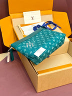 Teal Louis Vuitton monogram bag with top zipper and blue strap, laid across a box