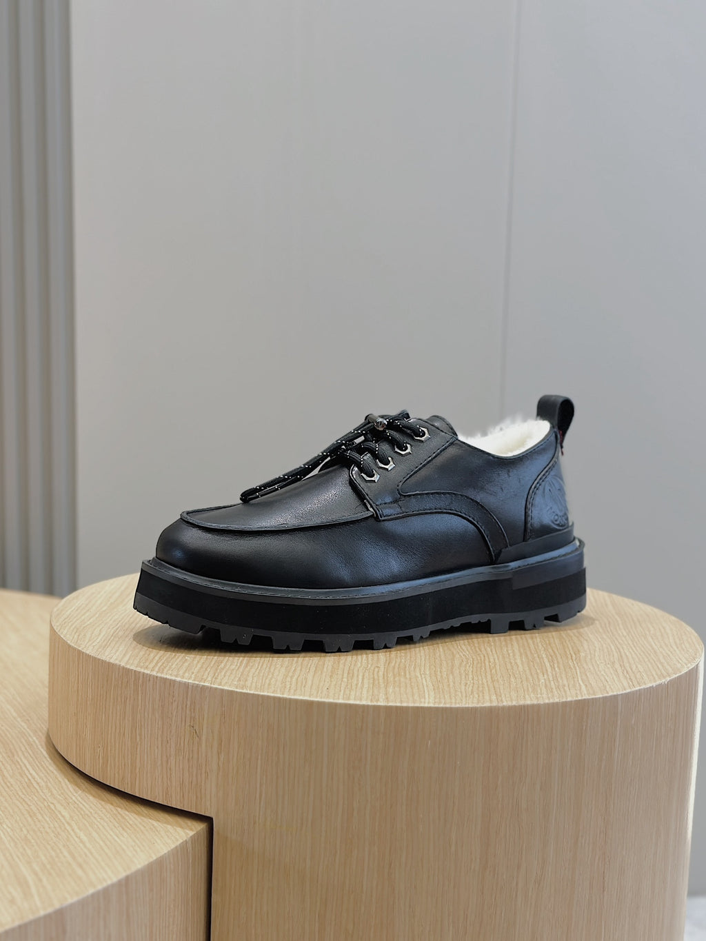 Black leather lace-up shoe, side profile with lace-up eyelets and treaded sole.