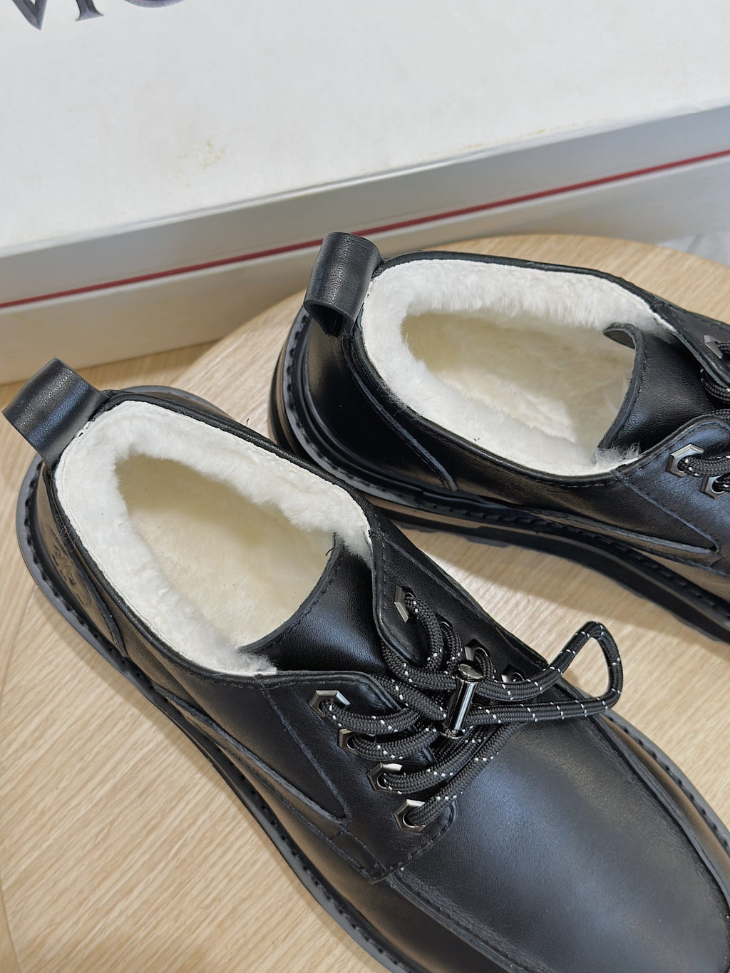 Black leather lace-up shoe close-up, stitched details, textured laces and cushioned lining.