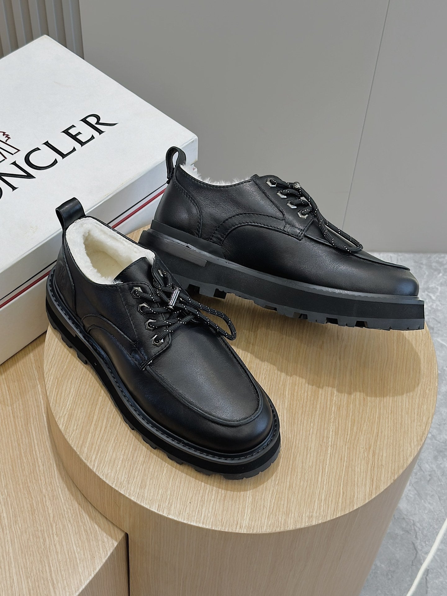 Black leather lace-up shoes with chunky sole and laces, shown on display.