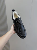 Black leather lace-up shoe with padded white lining and chunky sole, side view.