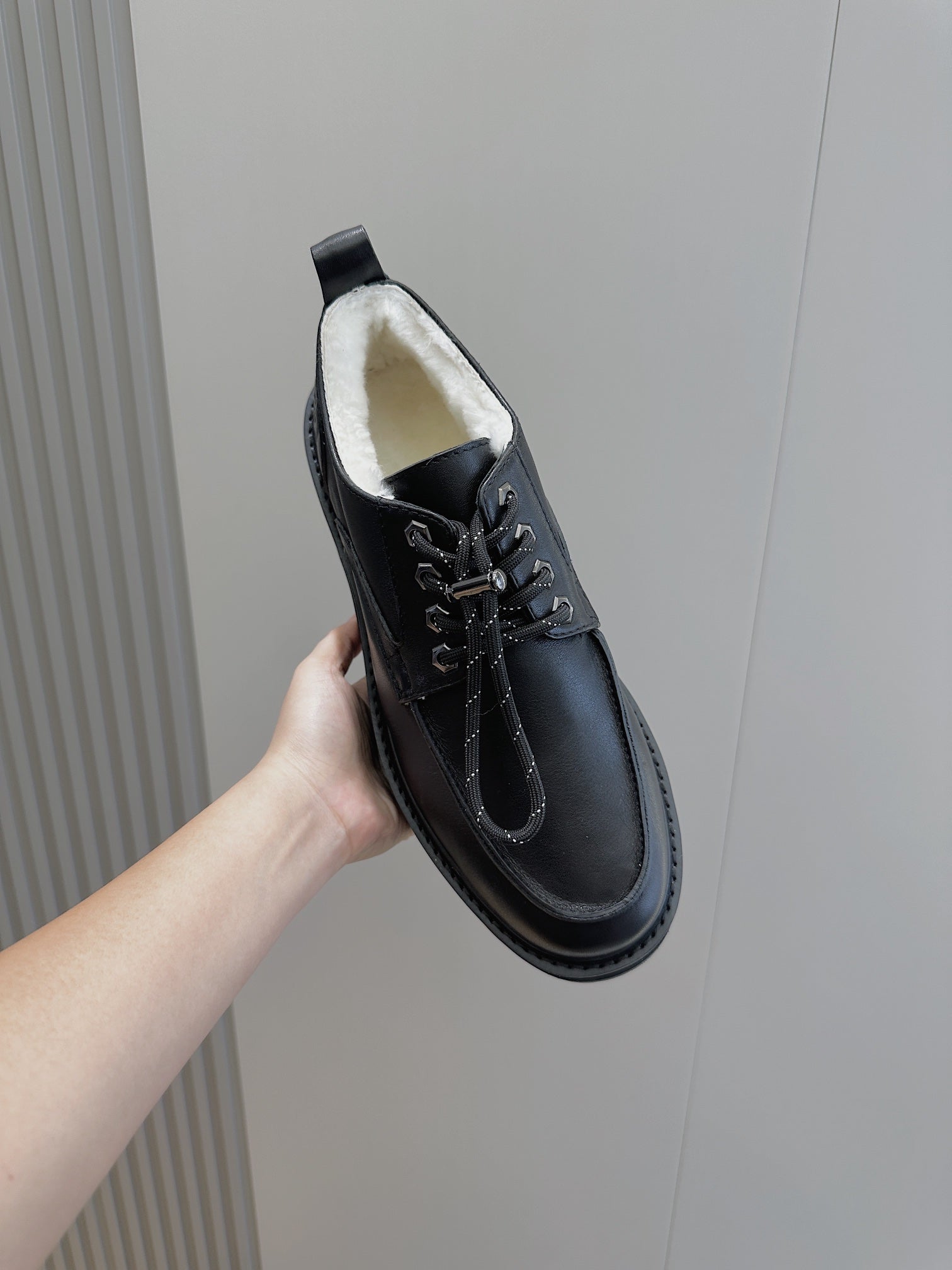 Black leather lace-up shoe with padded white lining and chunky sole, side view.