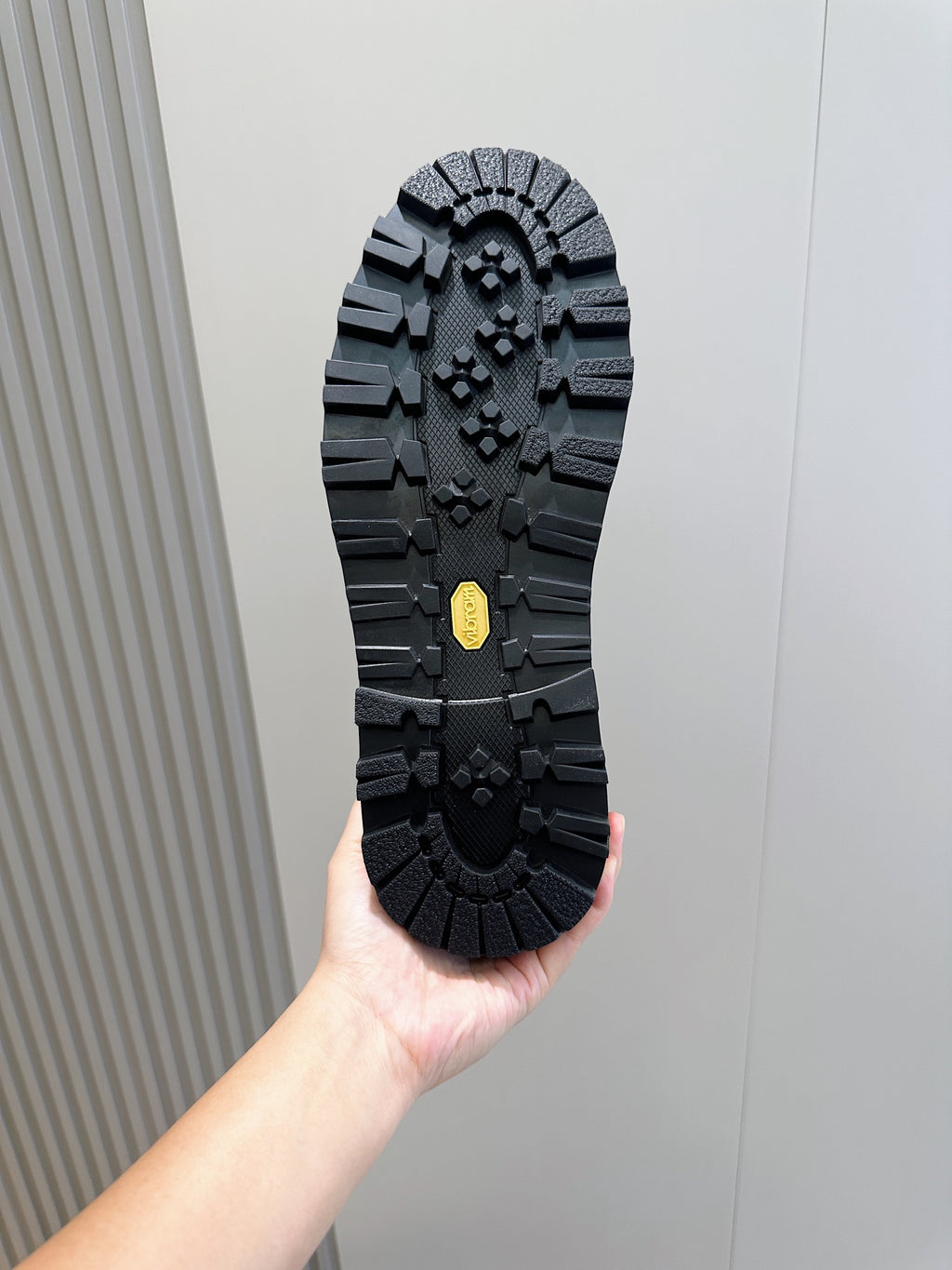 Black shoe outsole with rugged tread pattern and rubber traction grips.
