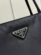 Prada logo patch on black tote bag front with metal-trim border