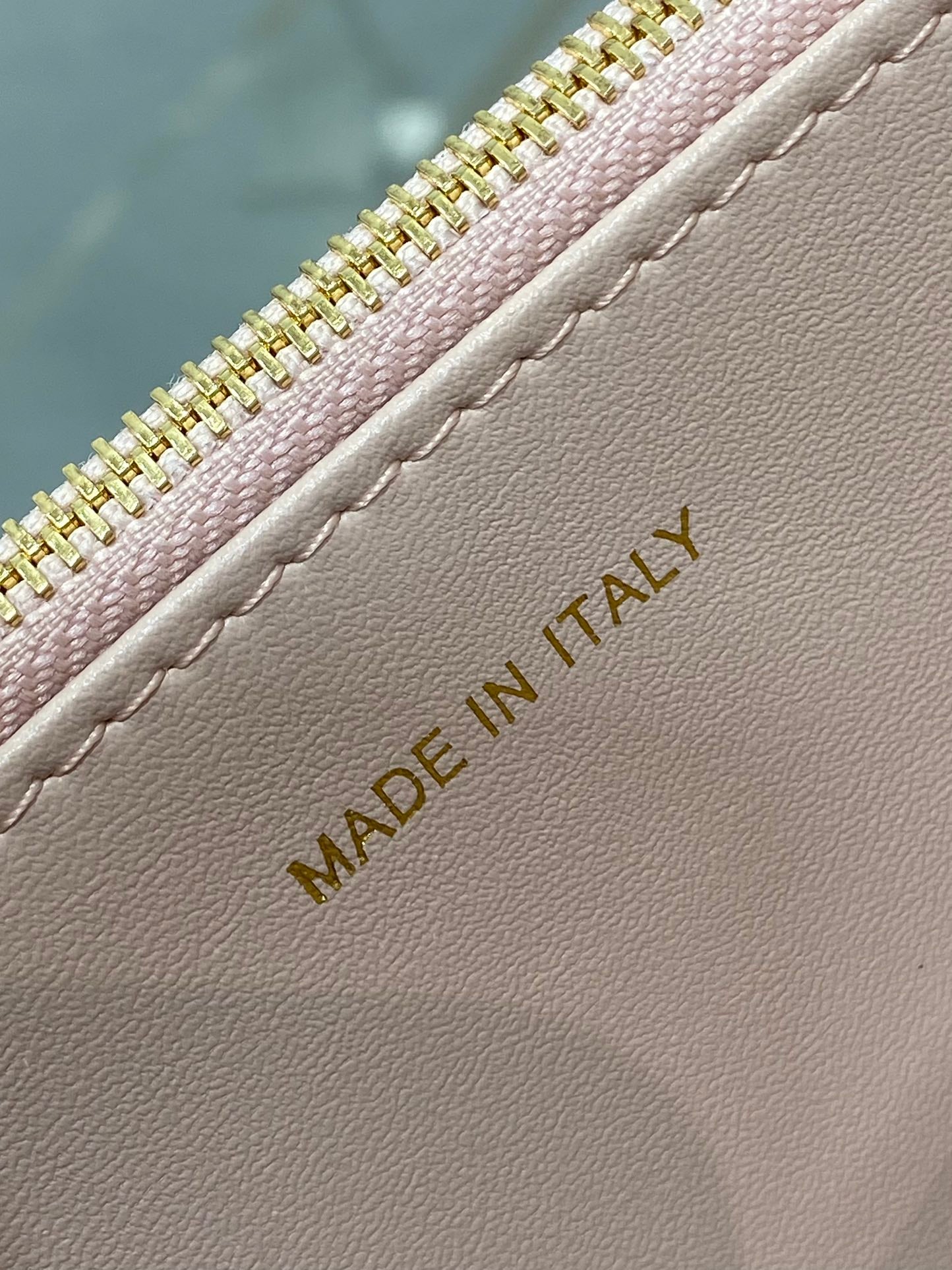 Made in Italy gold text on pale pink leather near zipper seam