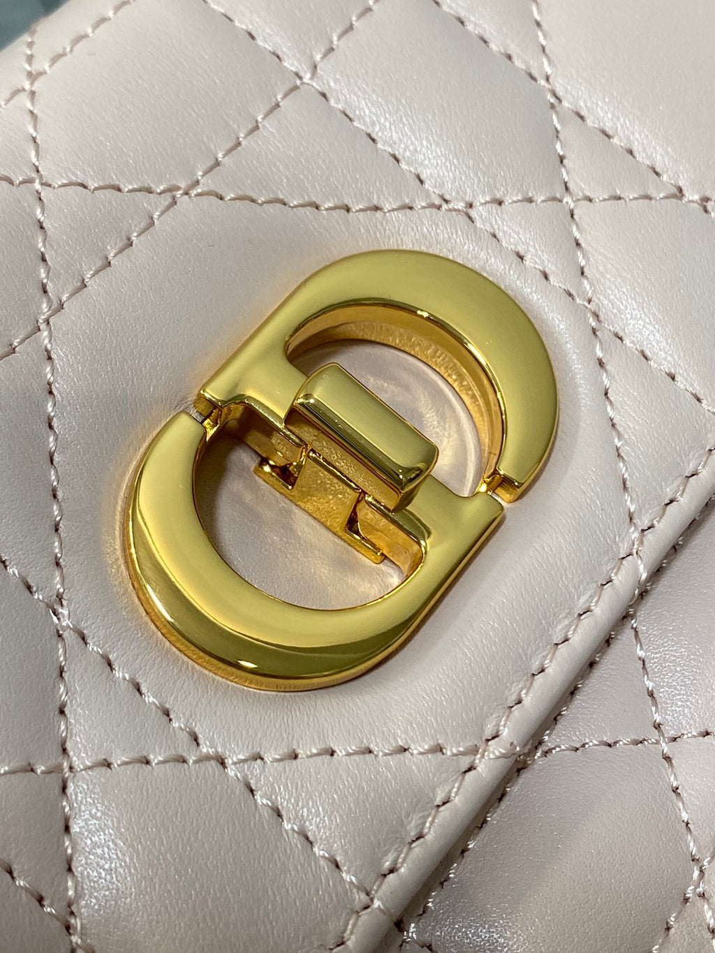 Dior bag close-up of gold CD logo on quilted pale pink flap