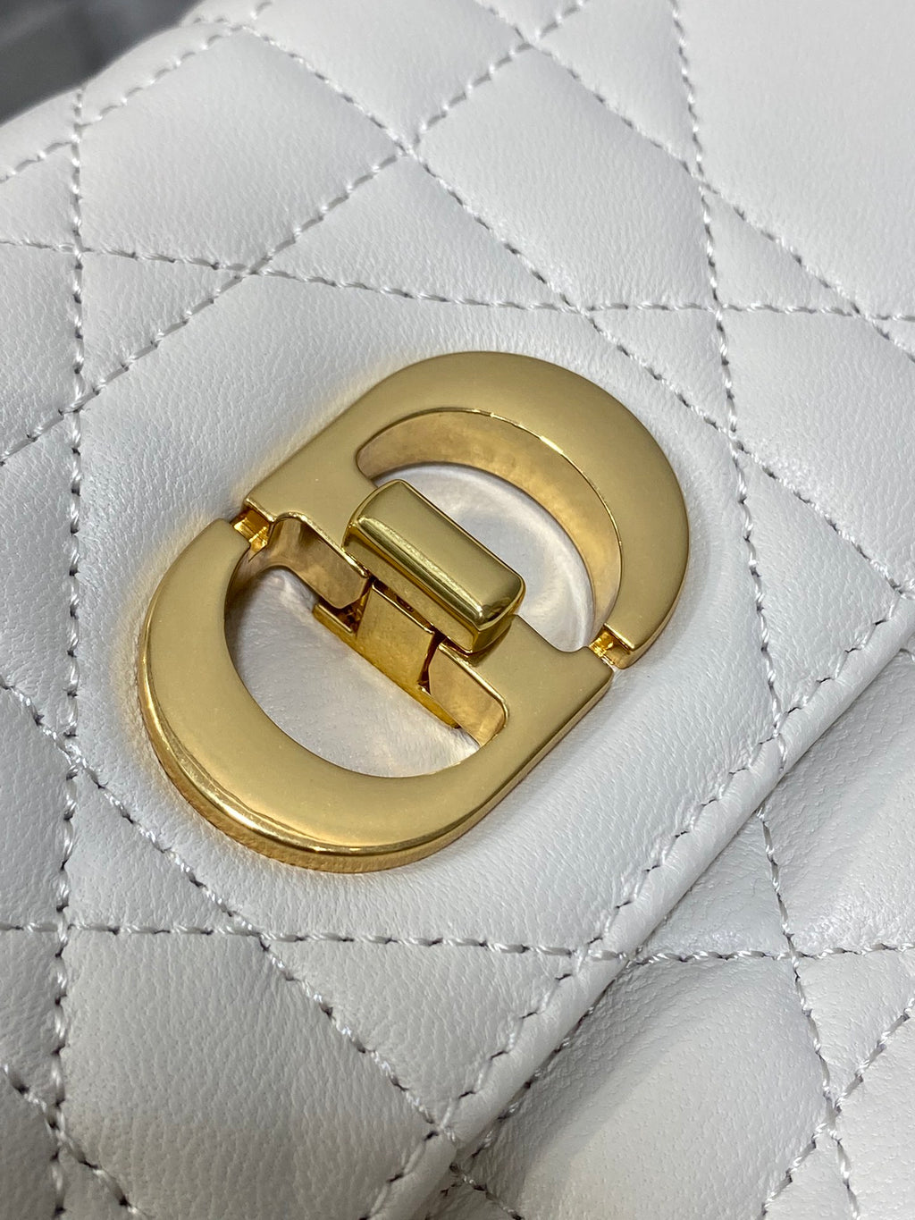 Dior handbag clasp close-up: gold CD logo on quilted white leather